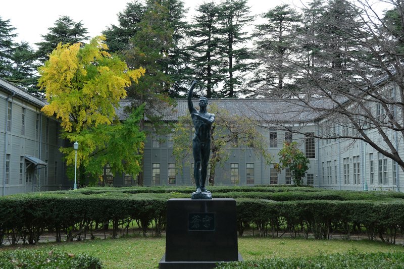 彫像と木造建物、色づく木。